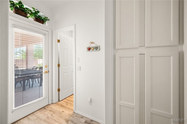 doorway featuring light wood-style floors and baseboards