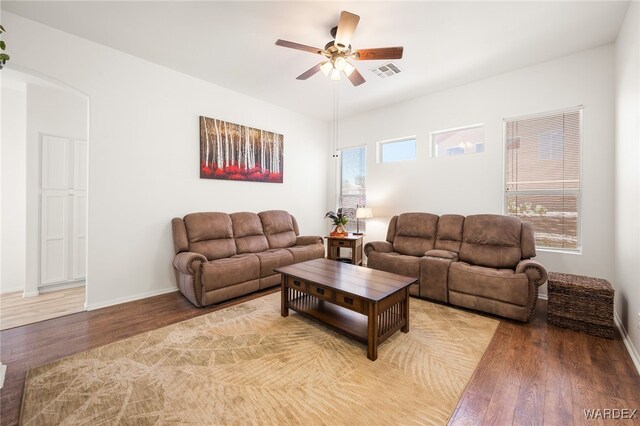 living room featuring arched walkways, visible vents, ceiling fan, wood finished floors, and baseboards