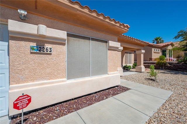 doorway to property with a tile roof and stucco siding