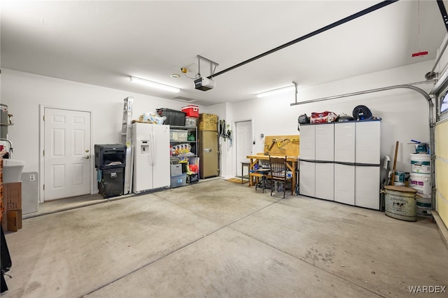 garage with a garage door opener, white refrigerator with ice dispenser, and a sink