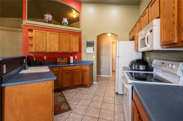 4875 N Famoso Dr, Kingman, AZ 86409 - kitchen featuring white appliances, a sink, arched walkways, brown cabinets, and light tile patterned flooring