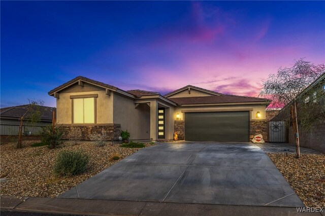 view of front of home with driveway, stone siding, an attached garage, fence, and stucco siding