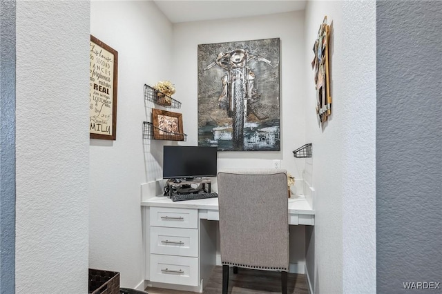 home office with built in study area and a textured wall