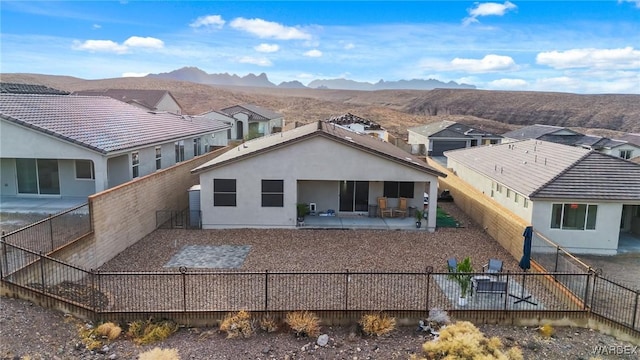 rear view of house featuring a patio, stucco siding, a mountain view, a residential view, and a fenced backyard