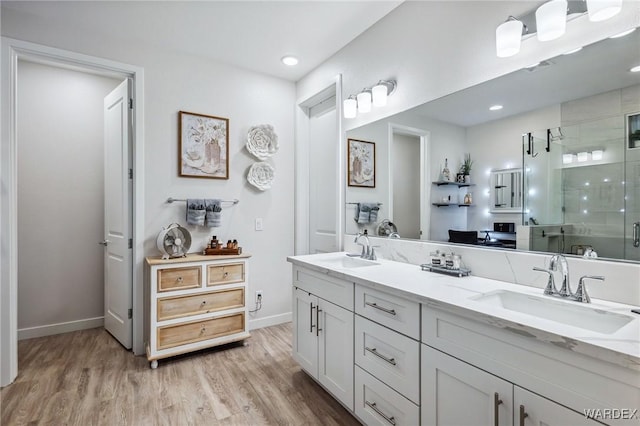 full bath featuring double vanity, wood finished floors, a sink, and a shower stall