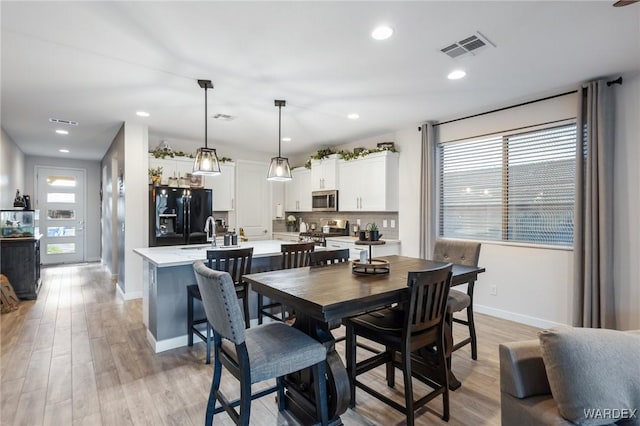 dining area with light wood-style flooring, visible vents, and recessed lighting