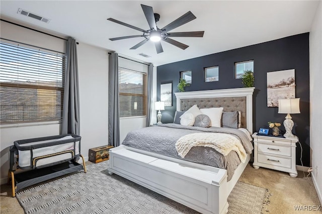 bedroom with baseboards, visible vents, a ceiling fan, and light colored carpet