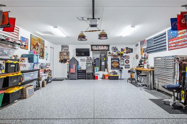 garage with a garage door opener, a workshop area, and electric water heater