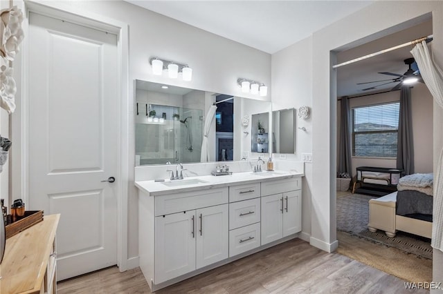 full bath featuring double vanity, a ceiling fan, a sink, and wood finished floors