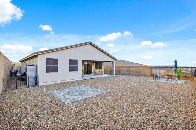 rear view of property with a fenced backyard, a patio, and stucco siding