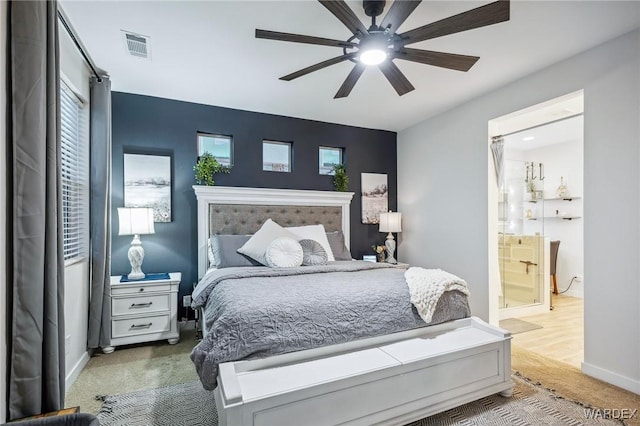 carpeted bedroom featuring a ceiling fan, visible vents, baseboards, and ensuite bathroom