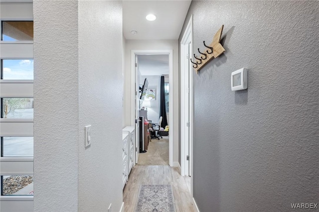 hall featuring a textured wall and light wood-type flooring