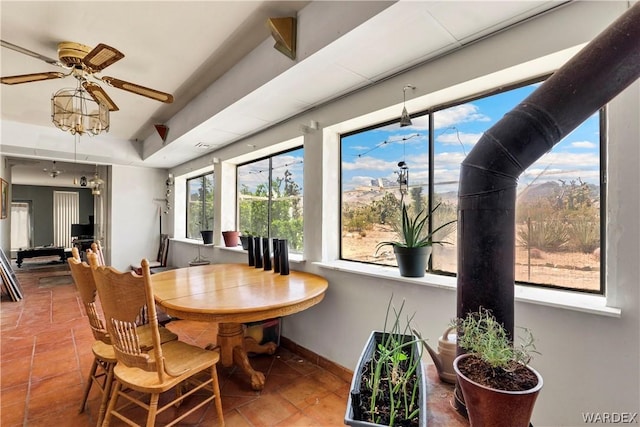 tiled dining space with ceiling fan and baseboards