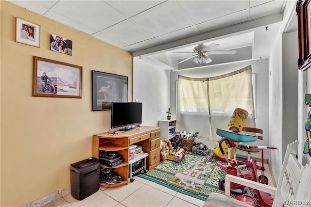 game room featuring light tile patterned floors, a drop ceiling, and a ceiling fan