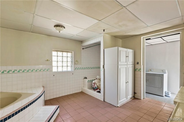 full bathroom featuring tiled bath, washer / clothes dryer, tile patterned floors, a paneled ceiling, and tile walls