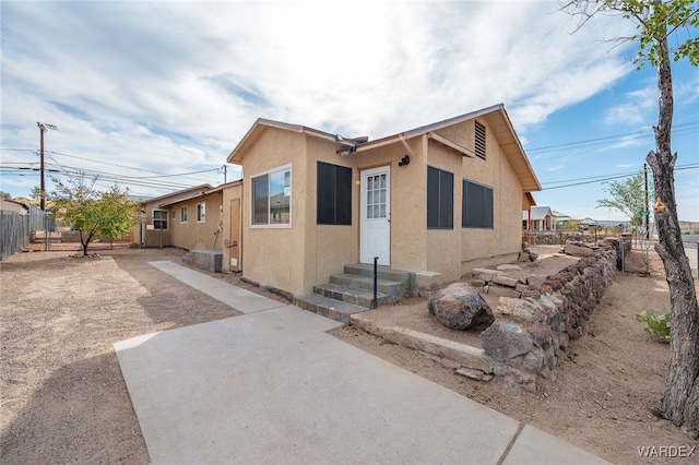 view of front of property featuring entry steps, fence, and stucco siding