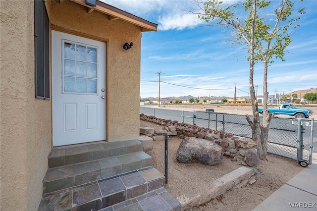 property entrance with fence and stucco siding