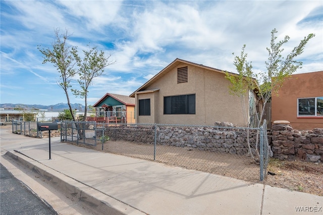 view of front of house with a fenced front yard, a mountain view, and stucco siding