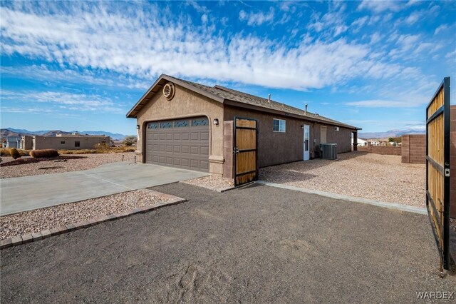 exterior space featuring concrete driveway, stucco siding, an attached garage, and central AC unit