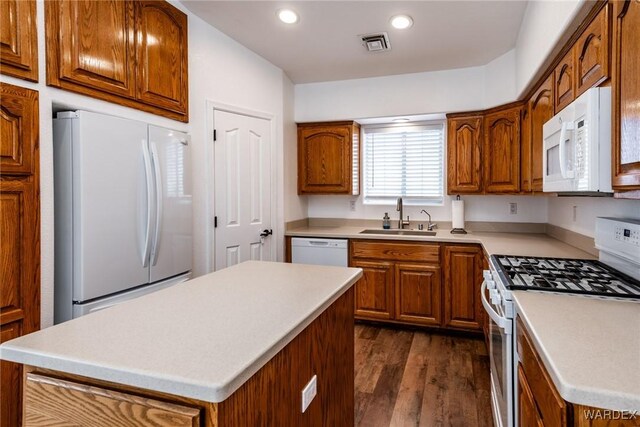 kitchen featuring a center island, white appliances, light countertops, and a sink