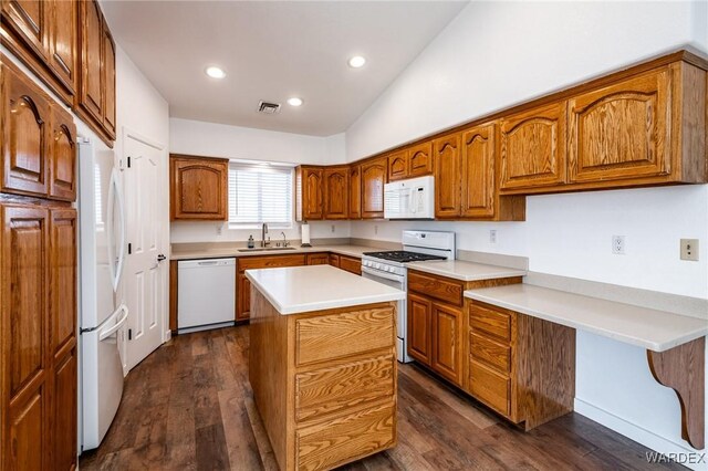 kitchen with a center island, light countertops, brown cabinetry, a sink, and white appliances