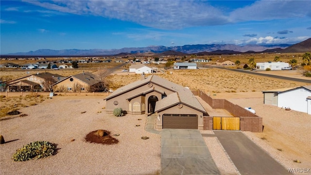 view of front of home featuring driveway, an attached garage, a residential view, and a mountain view