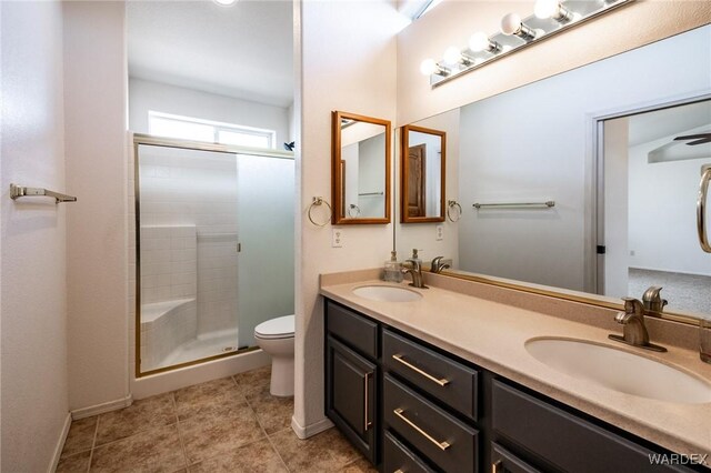 bathroom featuring a sink, a shower stall, toilet, and double vanity