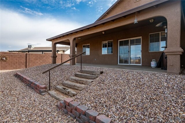 rear view of house featuring a patio area, fence, and stucco siding