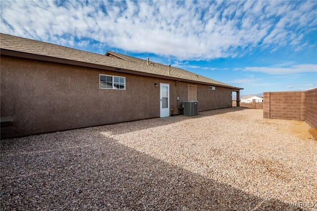 rear view of house featuring fence, cooling unit, and stucco siding