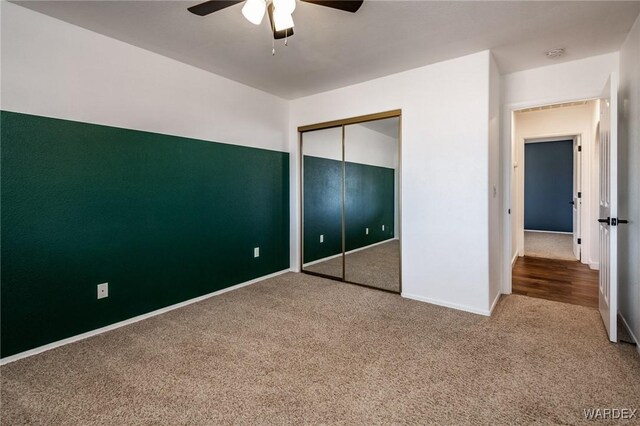 unfurnished bedroom featuring carpet, a closet, ceiling fan, and baseboards