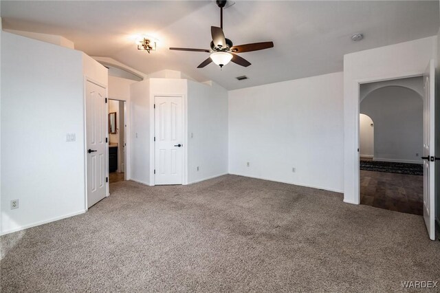 unfurnished bedroom featuring arched walkways, ceiling fan, carpet floors, visible vents, and vaulted ceiling