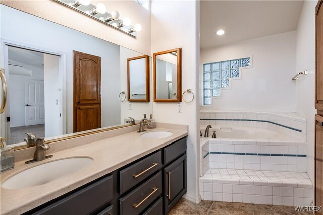 bathroom with a relaxing tiled tub, a sink, and double vanity