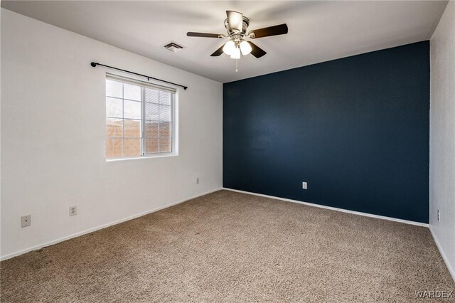 spare room with ceiling fan, carpet floors, visible vents, and baseboards