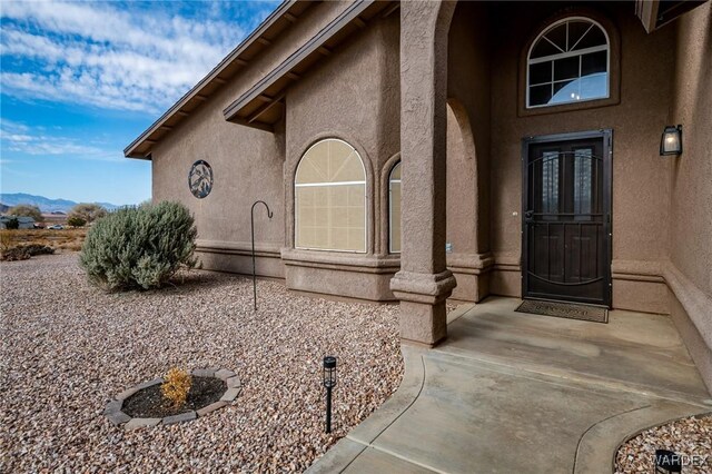 doorway to property with a mountain view, a patio, and stucco siding