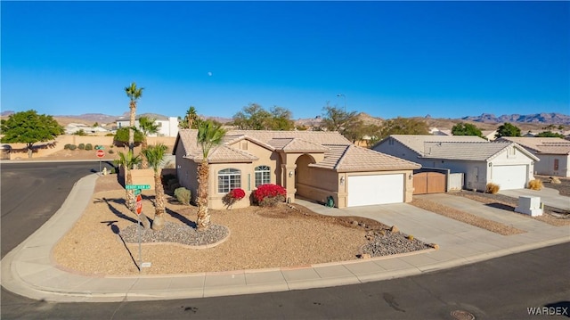 view of front of property featuring stucco siding, an attached garage, a mountain view, driveway, and a tiled roof