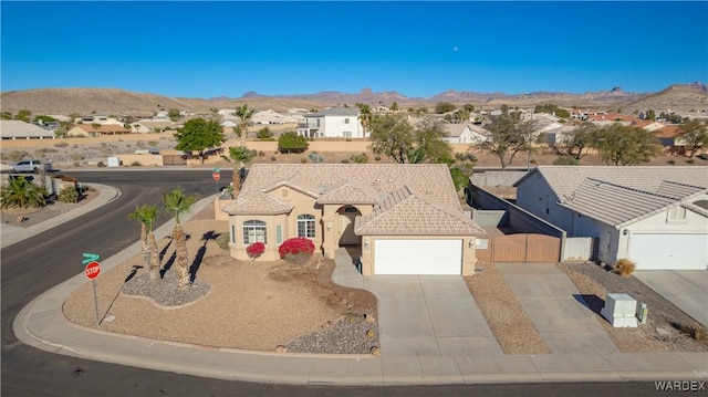 view of front of home featuring concrete driveway, a residential view, an attached garage, a mountain view, and stucco siding