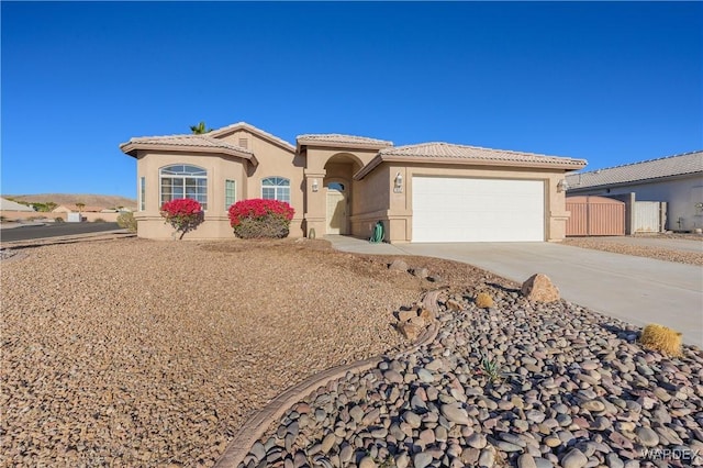 view of front facade featuring a garage, concrete driveway, a tile roof, and stucco siding