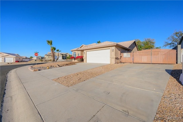 view of front of property featuring stucco siding, concrete driveway, an attached garage, fence, and a residential view