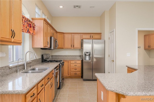 kitchen with stainless steel appliances, visible vents, a sink, and light stone countertops