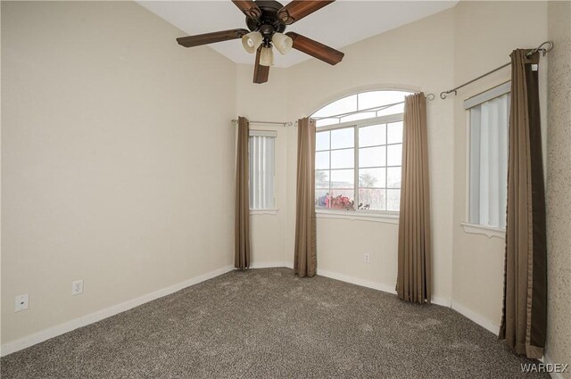 unfurnished room with baseboards, dark carpet, and ceiling fan