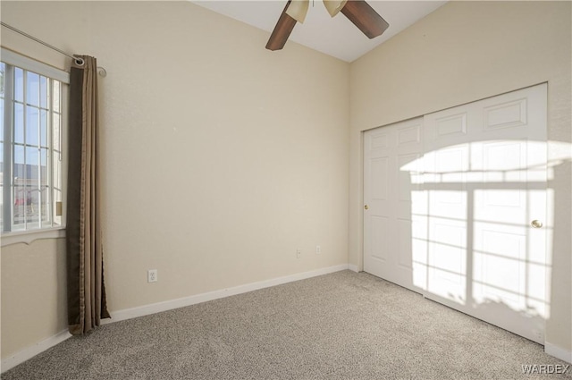 carpeted empty room featuring baseboards and a ceiling fan