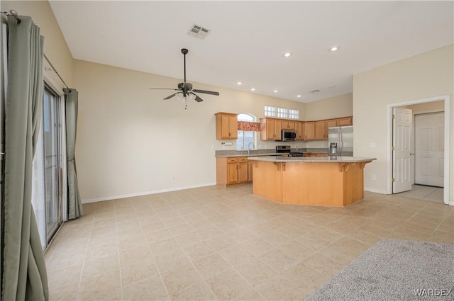 kitchen featuring a sink, a kitchen breakfast bar, baseboards, appliances with stainless steel finishes, and a center island