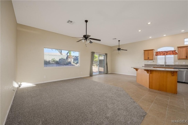 kitchen with a breakfast bar, visible vents, stainless steel dishwasher, open floor plan, and baseboards