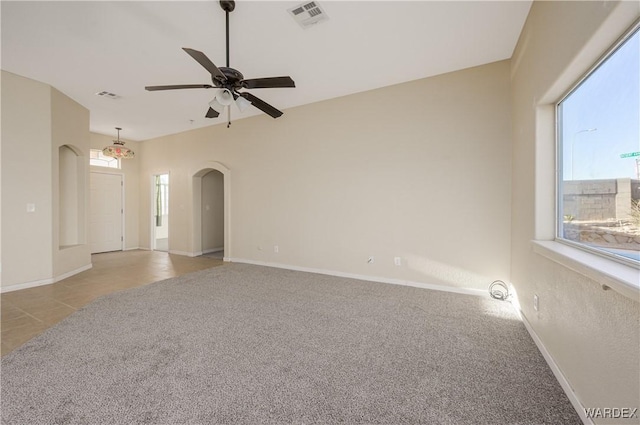 empty room featuring arched walkways, light carpet, visible vents, and baseboards