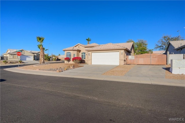 view of front of house with an attached garage, a tile roof, concrete driveway, a residential view, and stucco siding