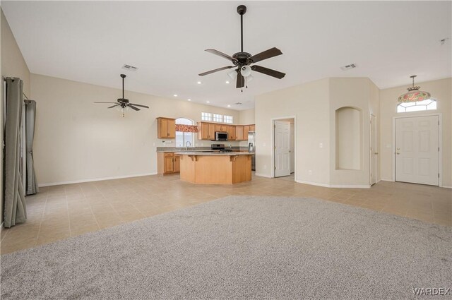 kitchen featuring ceiling fan, a kitchen island, stainless steel microwave, open floor plan, and a wealth of natural light