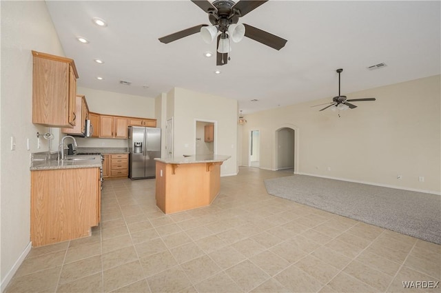 kitchen featuring a center island, arched walkways, stainless steel refrigerator with ice dispenser, visible vents, and open floor plan