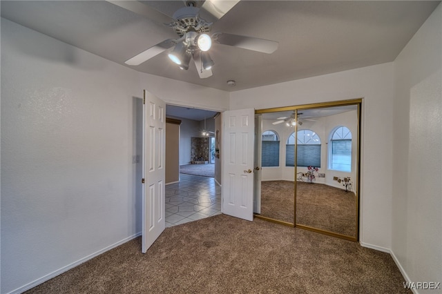 unfurnished bedroom featuring tile patterned floors, a ceiling fan, a closet, carpet, and baseboards