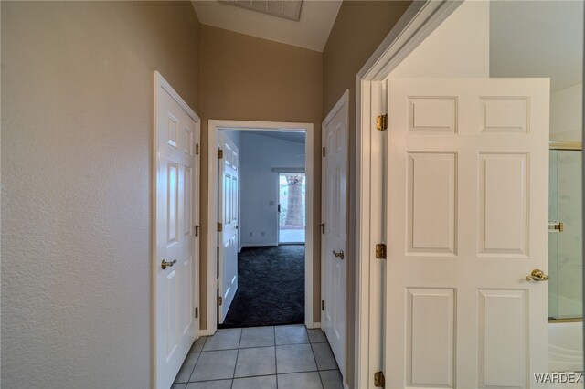 corridor featuring light colored carpet, light tile patterned floors, baseboards, and visible vents