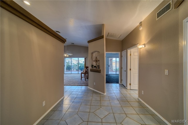 corridor with lofted ceiling, light tile patterned floors, baseboards, and visible vents